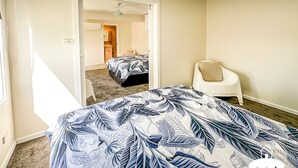 Une chambre à coucher avec un lit, une chaise et une salle de bain visible à travers une porte ouverte.