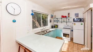 Une cuisine de taille réduite, équipée d’un évier, d’une cuisinière et d’un four à micro-ondes.