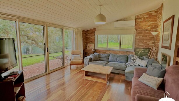 A living room with a wooden floor, a grey sofa, a coffee table, and a TV.