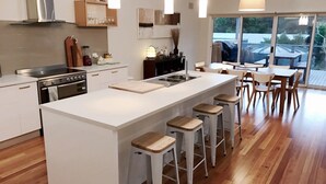 A modern kitchen with a central island, bar stools, and a dining area with chairs.