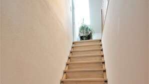 A wooden staircase with a light-colored wall on one side and a window at the top. - Modern apartment in the countryside (Niedertaufkirchen)