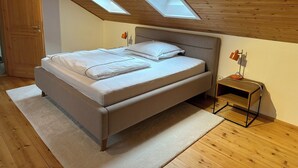 A bedroom with a bed, a nightstand, a lamp, and skylights. - Modern apartment in the countryside (Niedertaufkirchen)