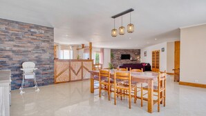 A spacious living area with a dining table, chairs, a kitchen area, and a seating area with a sofa and TV. - Charmante Maison avec piscine (La Douze)