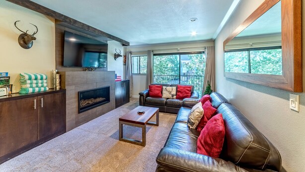 Una sala de estar moderna con chimenea, sofá de cuero y un amplio ventanal con vistas al exterior.