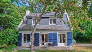 A two-story house with a grey roof, blue shutters, and a small patio with outdoor furniture. - Amazing home in Névez with WiFi (Névez)