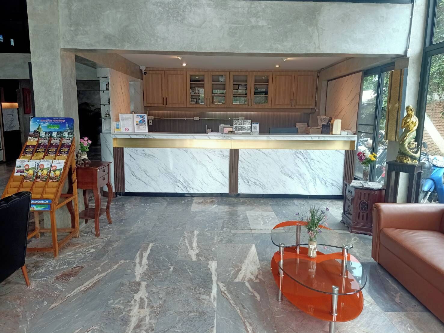 A reception area with a marble counter, wooden cabinets, a glass table, and a leather couch.