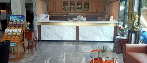 A reception area with a marble counter, wooden cabinets, a glass table, and a leather couch.