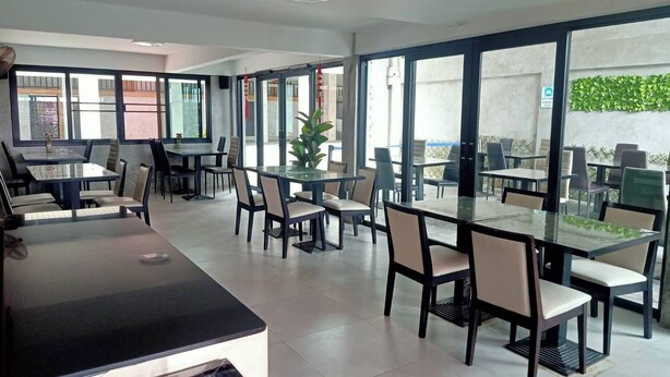 A modern dining area with glass partitions, tables, and chairs. - Mapeak Hotel (Chiang Mai)