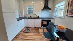 A modern kitchen with white cabinets, a black stove, and a dining area with a table and chairs.