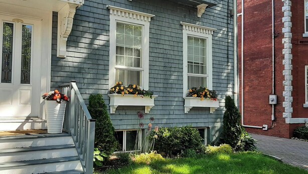 A two-story house with a front porch, a mailbox, and flower boxes on the windows.