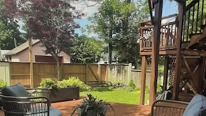 An outdoor patio area with two wicker chairs, a small round table, and a striped rug.