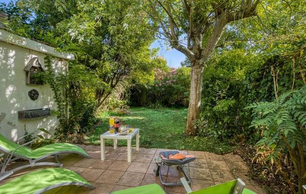 A patio with a table, chairs, and a wheelbarrow. - Charmante Maison Proche Plage (La Rochelle)