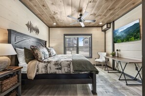 A bedroom with a bed, a ceiling fan, a window with blinds, a desk, and a chair. - Sleeps 21 | Indoor Pool | Resort Waterpark | Views (Sevierville)