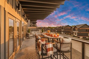 A balcony with outdoor seating, a table with a drink, and a view of other buildings. - Sleeps 21 | Indoor Pool | Resort Waterpark | Views (Sevierville)