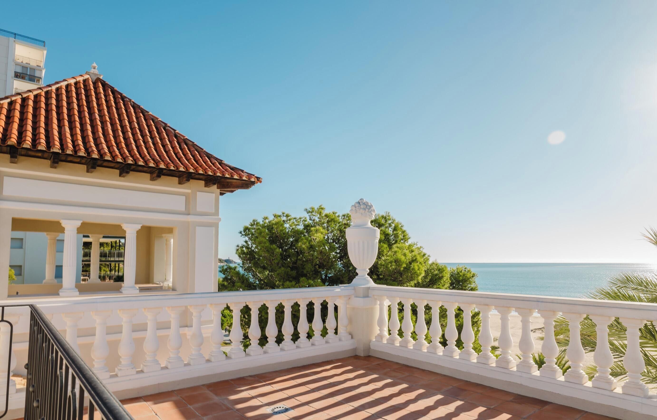 Un balcon doté d’une balustrade blanche, d’un toit recouvert de tuiles et offrant une vue sur la mer.