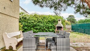 An outdoor patio with wicker furniture, a stone table, and a stone fireplace.