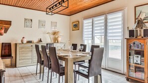 A dining area with a wooden table and chairs, a kitchen area with a cabinet, and a bookshelf with books.