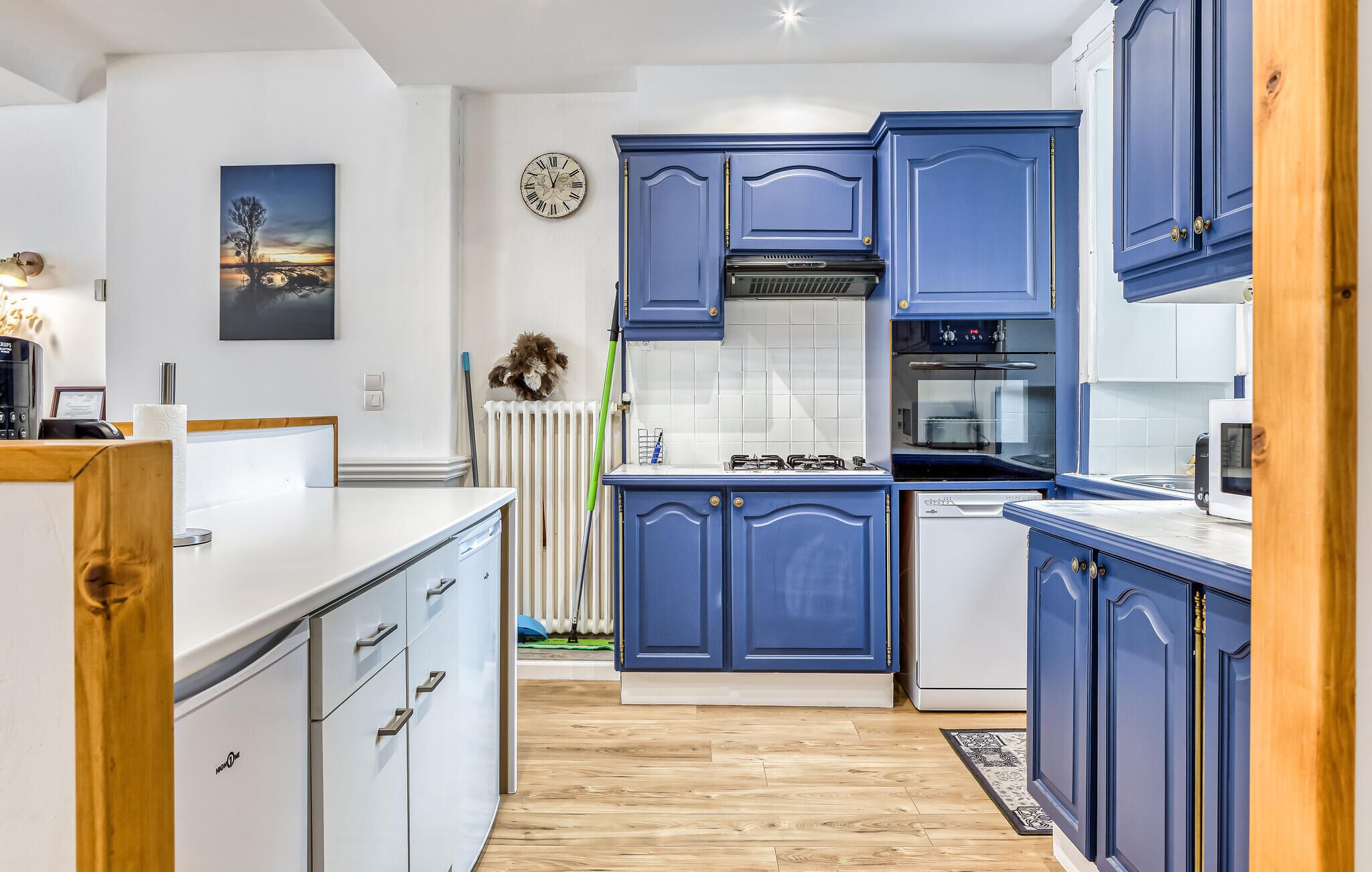 Une cuisine moderne avec des armoires bleues, une cuisinière à gaz, un four et une horloge au mur.