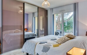 Une chambre à coucher moderne avec un grand lit, un miroir et une vue sur l’extérieur.