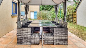 Une terrasse extérieure dotée d’une table couverte et de meubles en osier.