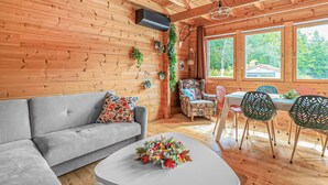 A cozy cabin interior with a grey sofa, floral-patterned armchair, and a dining table with chairs. - Lovely home in BOURBOURG with WiFi (BOURBOURG)