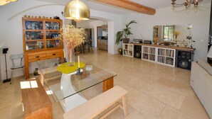 A spacious living area with a glass coffee table, a wooden bench, a bookshelf, and a kitchen in the background. - Amazing home in Venelles (Venelles)