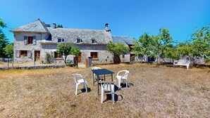 A stone house with a stone roof, a small garden with a table and chairs, and a bench.