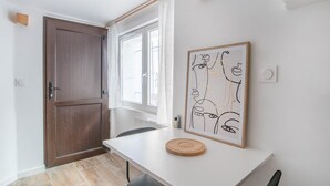 Una habitación moderna con una puerta de madera, una mesa blanca y una obra de arte abstracta enmarcada.