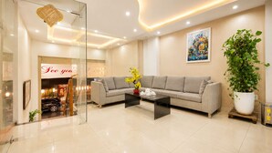 A modern living room with a sofa, coffee table, and a large potted plant. - Thu Ha Airport Hotel (Ho Chi Minh City)