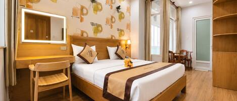 A hotel room with a wooden bed, a desk, a chair, a mirror, and a wardrobe.