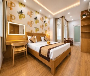 A hotel room with a wooden bed, a desk, a chair, a mirror, and a wardrobe. - Thu Ha Airport Hotel (Ho Chi Minh City)