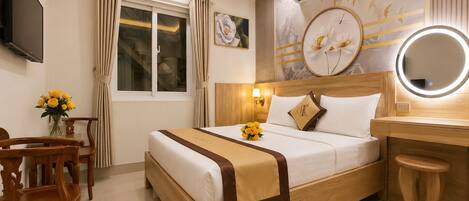 A hotel room with a bed, a desk, a chair, a TV, an air conditioner, and a window with curtains.