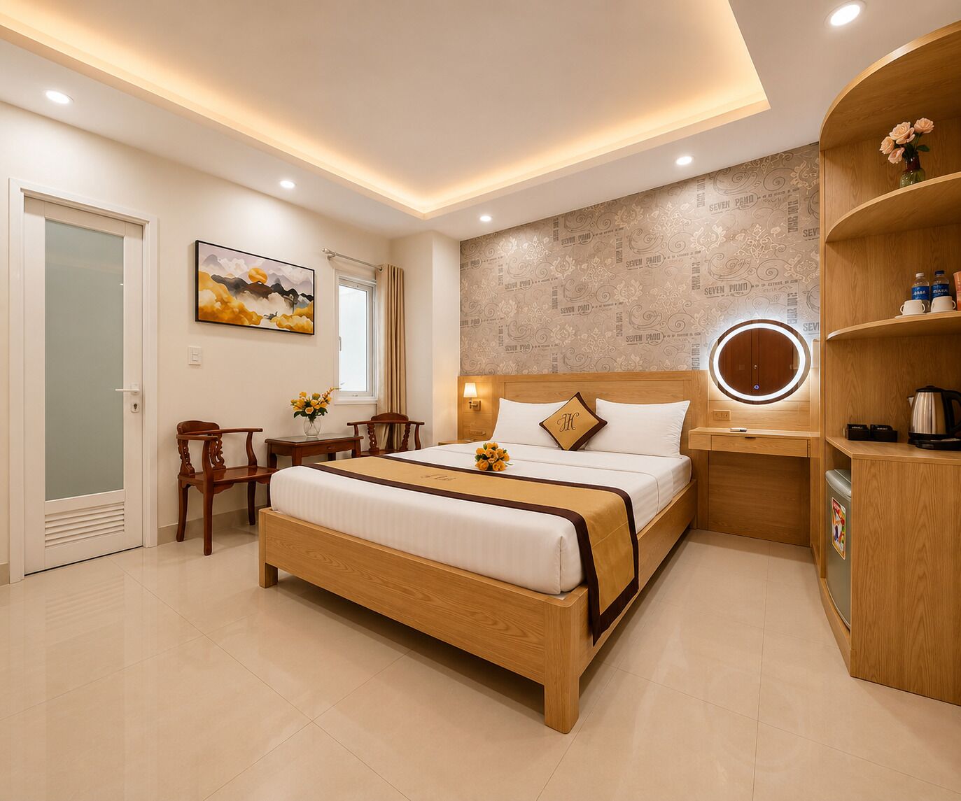 A modern hotel room with a wooden bed, a bedside table with a lamp, a round mirror, and a small seating area with a chair and a table.