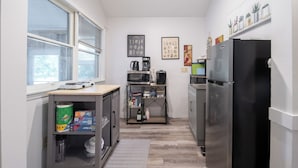 Een kleine keuken met een koelkast, magnetron en koffiezetapparaat op een plank.