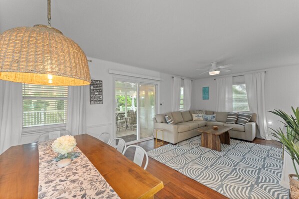 A spacious living room with a large sofa, a dining table with chairs, and a patterned rug.