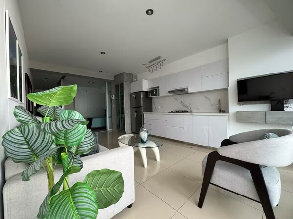 A modern living room with a sofa, a glass coffee table, and a dining area with a chair.