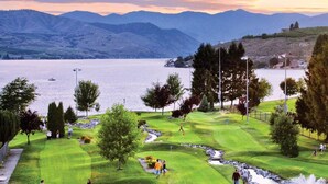 Een golfbaan met een meer en bergen op de achtergrond.