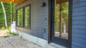A modern house with large windows, a covered porch, and a door leading to the interior. - Cozy 1 BR ADU | Private Access | Projector Theater (Windham)