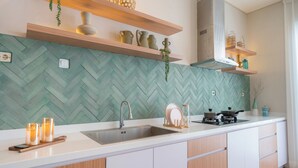 A modern kitchen with a herringbone tile backsplash, wooden shelves, and a stainless steel sink. - Villa Palma Blanca Canggu by Nagisa Bali (Kerobokan)