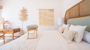 A bedroom with a bed, bedside table, lamp, and decorative wall hanging. - Villa Palma Blanca Canggu by Nagisa Bali (Kerobokan)