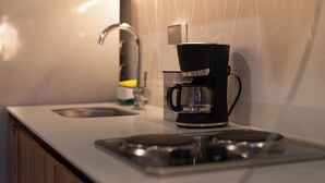 Eine moderne Küche mit einer schwarzen Kaffeemaschine auf der Arbeitsfläche, einem Edelstahl-Spülbecken und einer weißen Fliesenspiegel.
