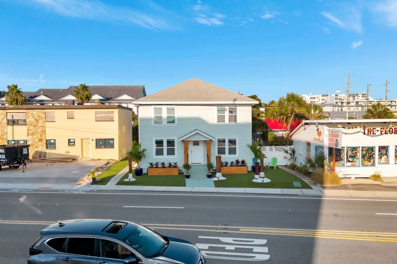 A two-story house with a front porch, a garage, and a small front yard with plants.