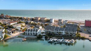 A coastal town with a marina, waterfront buildings, and a clear view of the ocean. - Tiki House  - Barefoot Breeze Walk to Beach (Treasure Island)