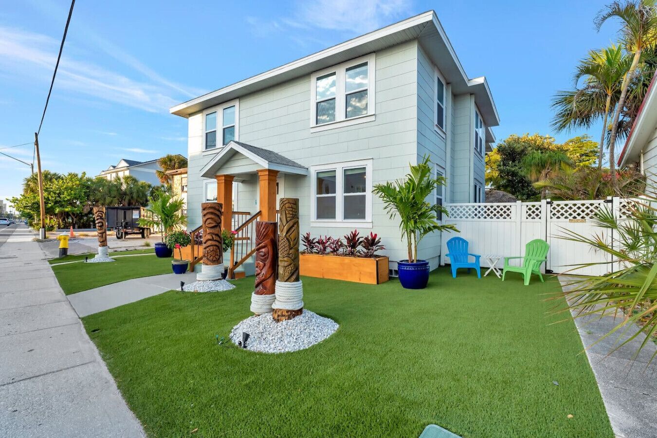 A two-story house with a front porch, a well-maintained lawn, and a white picket fence.