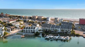 A coastal town with a marina, waterfront buildings, and a clear view of the ocean.