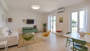A modern living room with a sofa, a green cabinet, a TV, and a dining area with chairs. - 3 bedroom beautiful home in Falerna (Falerna)