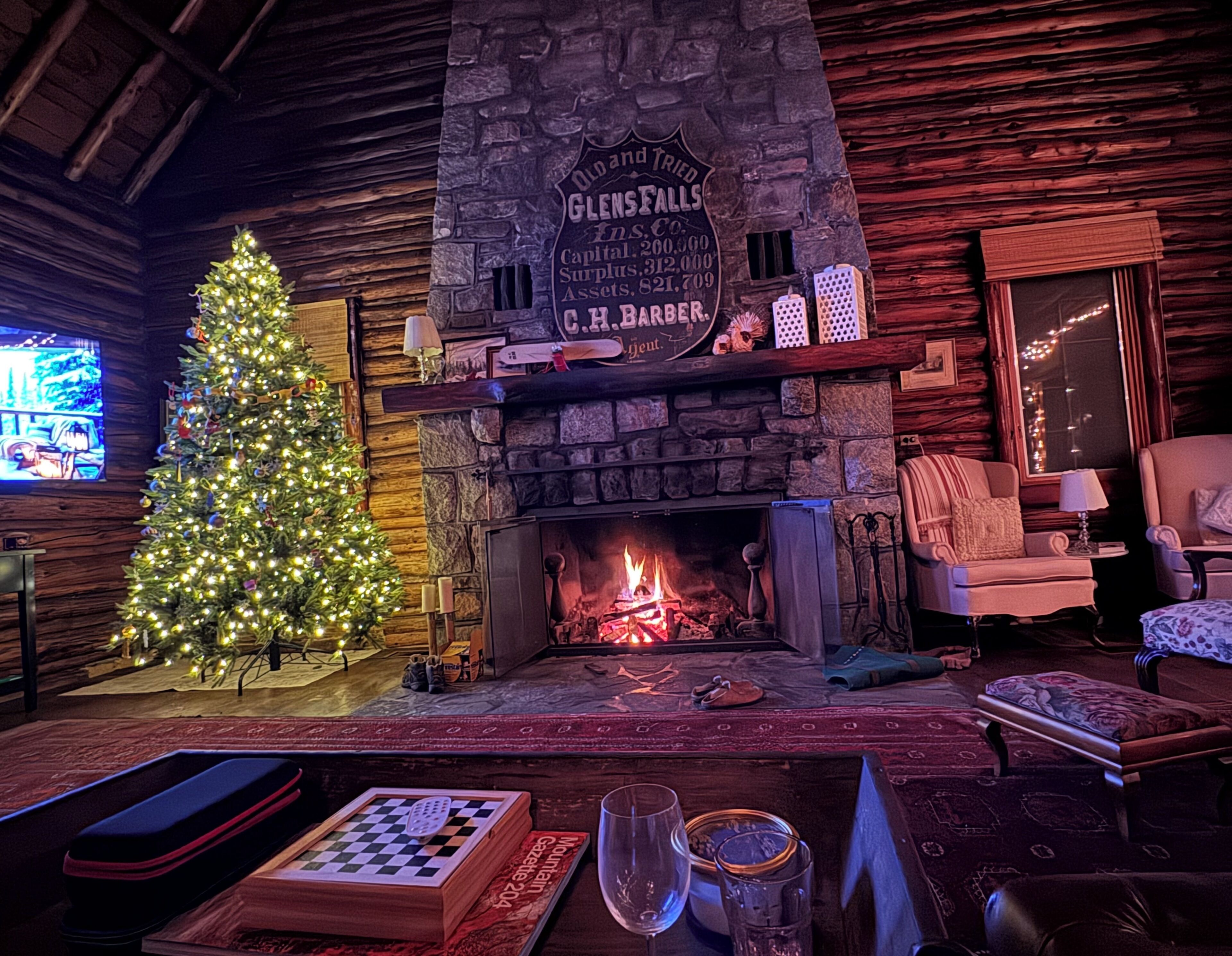 A cozy room with a stone fireplace, a Christmas tree, and a television.