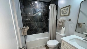 Une salle de bain moderne équipée d’une baignoire, de toilettes et d’un meuble-lavabo.