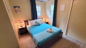 Ein Schlafzimmer mit einem Bett, zwei Nachttischen, einem Fenster und einer Tür.
