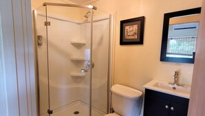 A bathroom with a glass-enclosed shower, a toilet, and a sink with a mirror above it. - Sunny studio in Esperanza (Vieques)